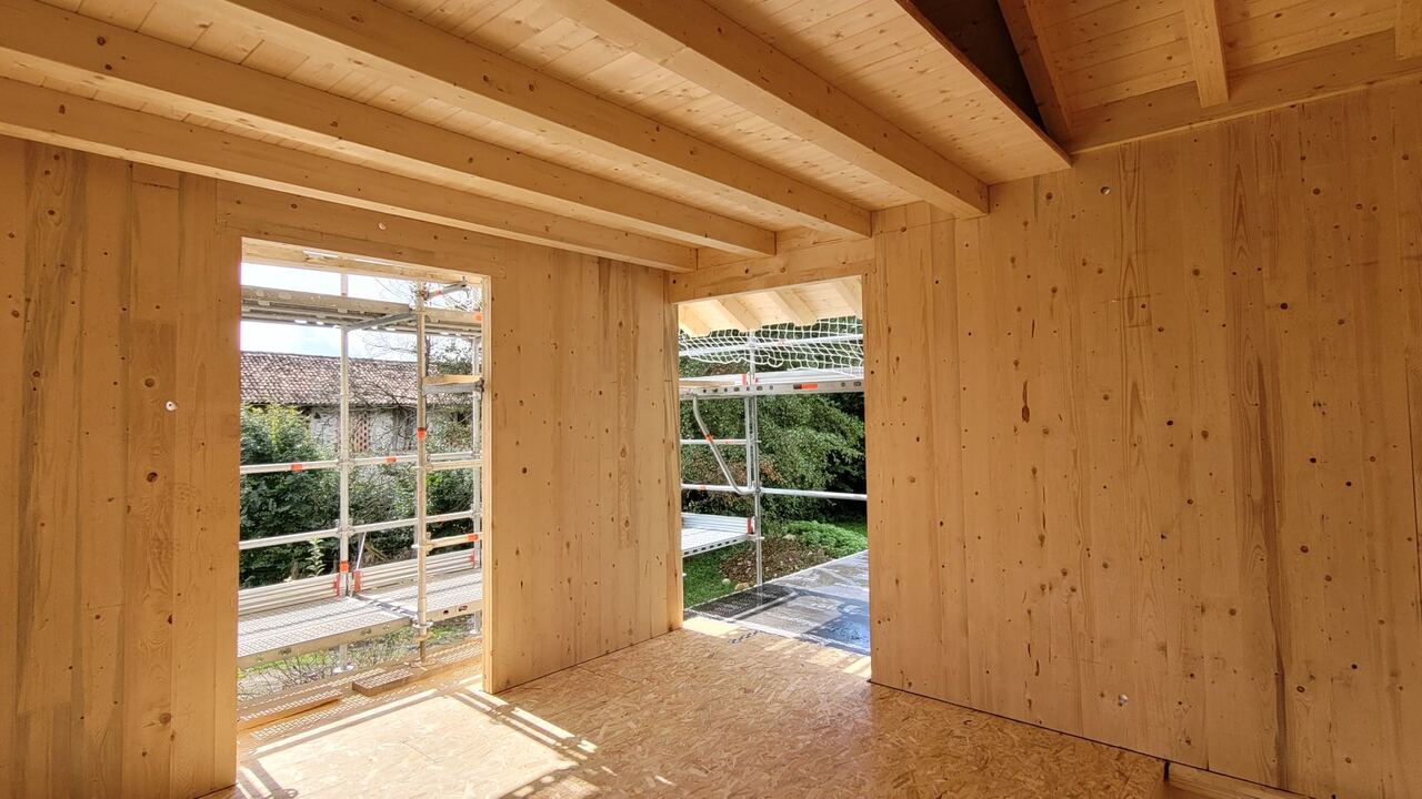 "Interno di casa in costruzione con pareti e solaio in pannelli XLAM, luce naturale dalle aperture — cantiere De Battista srl