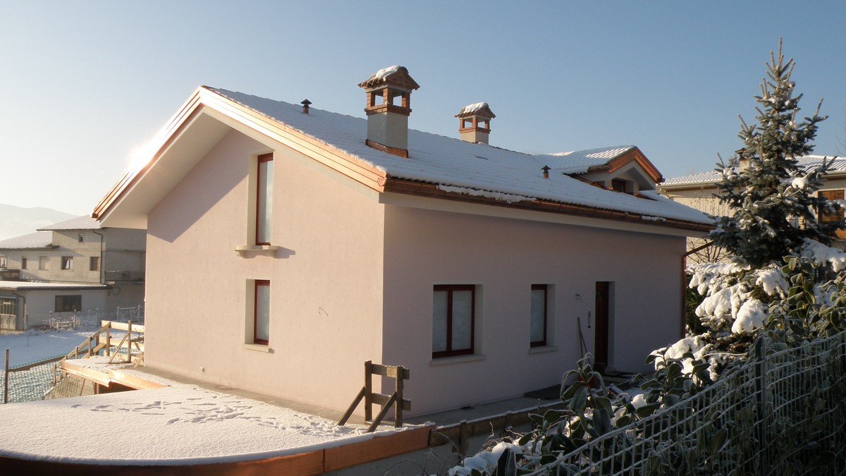 Casa nel Bellunese con neve sul tetto in una giornata invernale di sole - la distribuzione della neve rivela le dispersioni di calore dalla copertura
