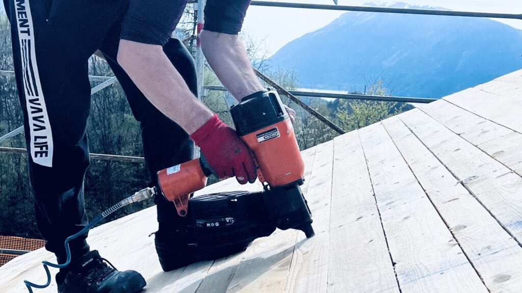 Operaio inchioda tavolato di ventilazione con chiodatrice pneumatica - copertura CasaClima Chies d’Alpago
