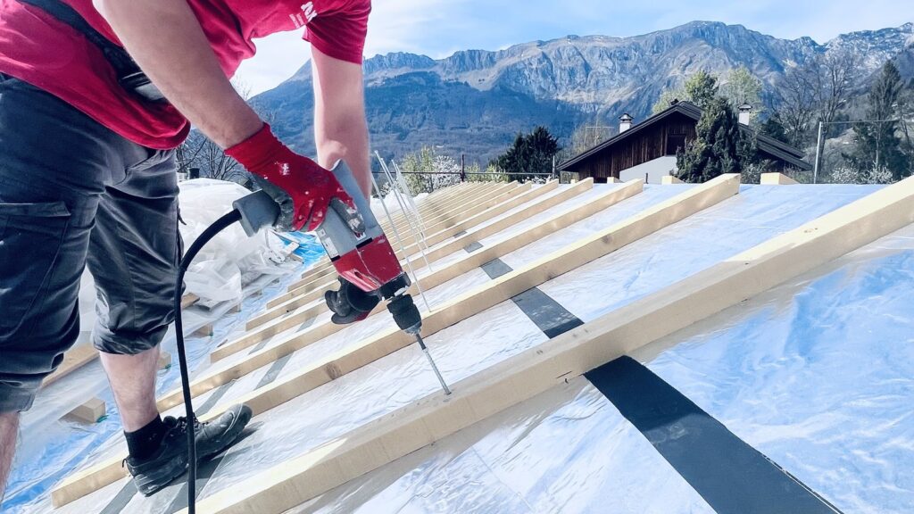 Operaio fissa listelli ventilazione con avvitatore su copertura CasaClima - cantiere Chies d’Alpago.