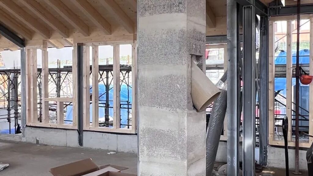 Camino prefabbricato a tutta altezza in un cantiere con struttura in acciaio e tetto in legno lamellare.