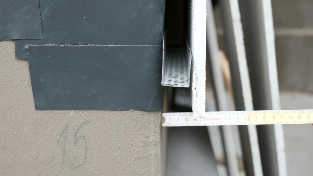 Dettaglio del bordo: membrana traspirante nera e profilo angolare in alluminio all’avvio della facciata ventilata.
