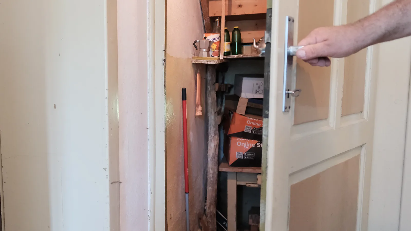 Mano che apre la porta di un sottoscala durante la visita di una casa