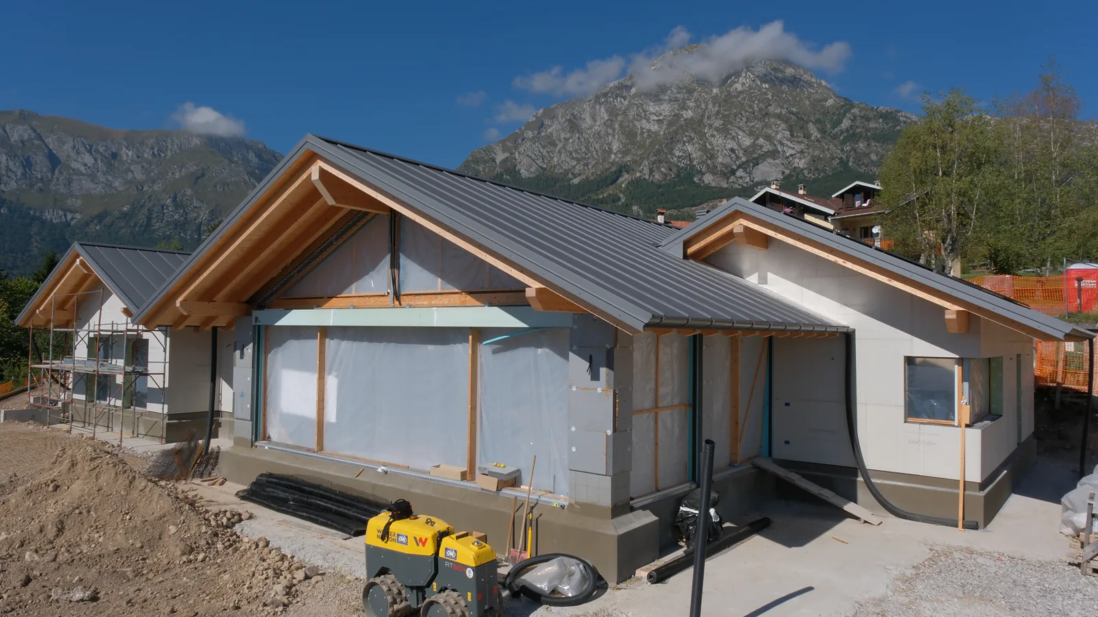 Casa in costruzione a Irrighe con tetto in metallo, travi in legno lamellare a vista e pareti ancora coperte dai teli.