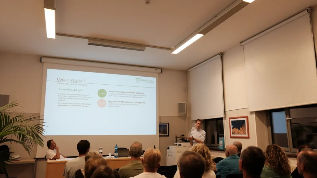 Lewis Dal Magro in piedi durante la serata, sullo schermo lo schema della verifica catastale del 15%. 